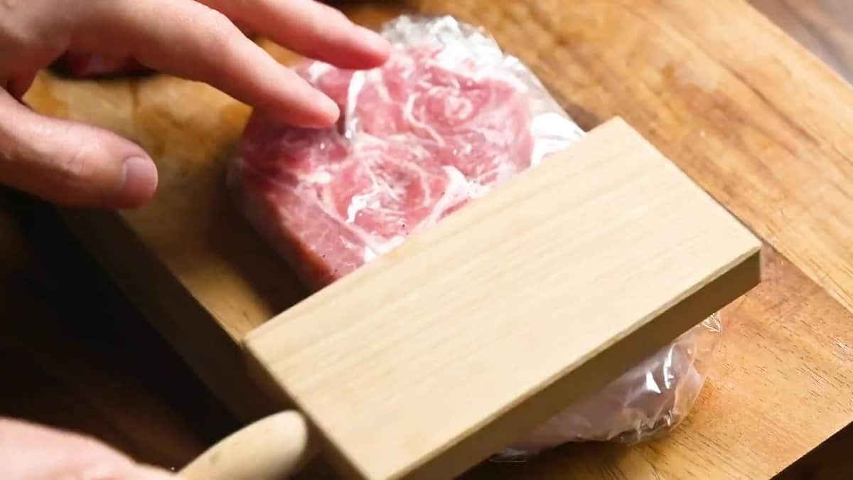 Pounding pork chops to an even thickness with a meat mallet to make tender Japanese tonkatsu.