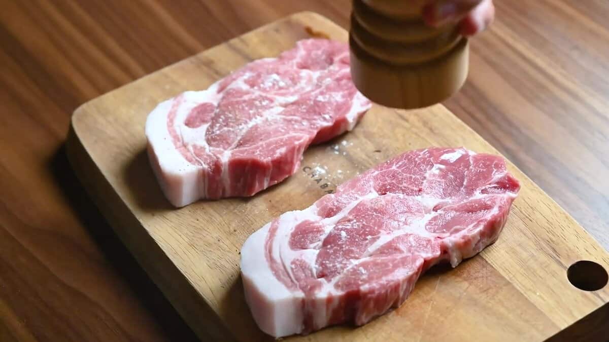 Seasoning pork loin chops with salt and freshly ground pepper.