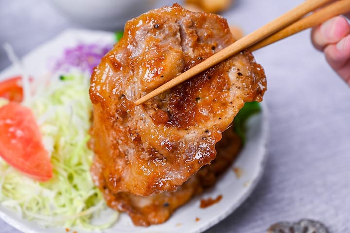 A slice of shogayaki ginger pork held with chopsticks