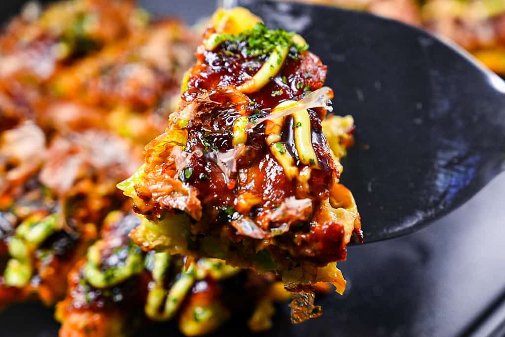 Holding piece of okonomiyaki with spatula