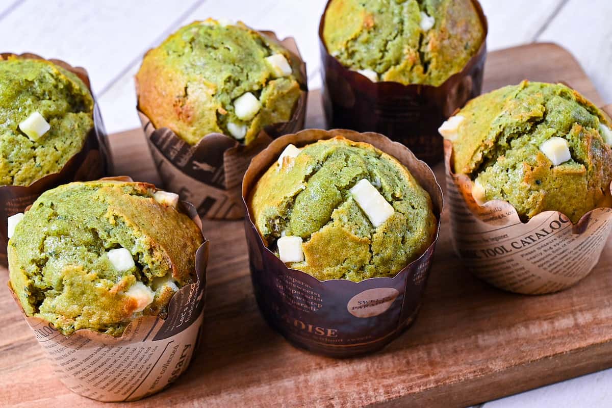 Matcha muffins with white chocolate chips on a wooden chopping board
