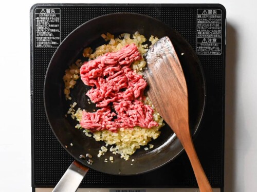 mince meat added to a frying pan with softened onions