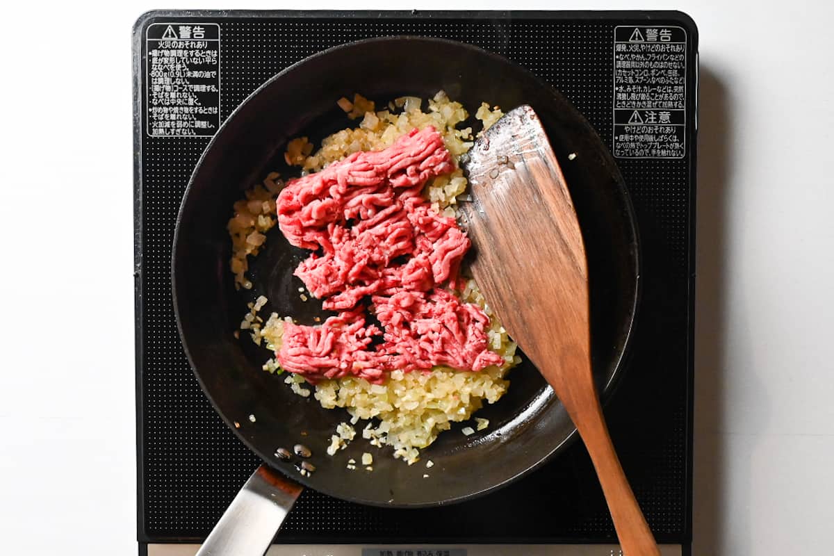 mince meat added to a frying pan with softened onions