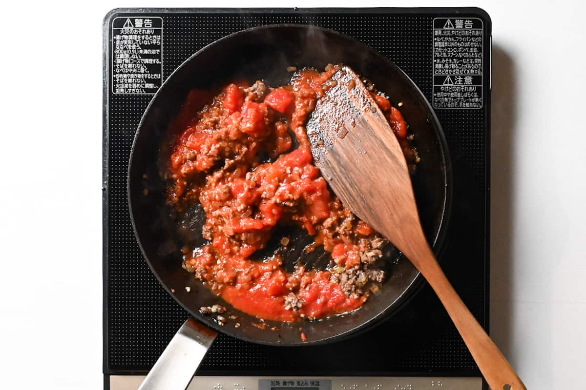 tinned tomato added to frying pan with mince meat and onions