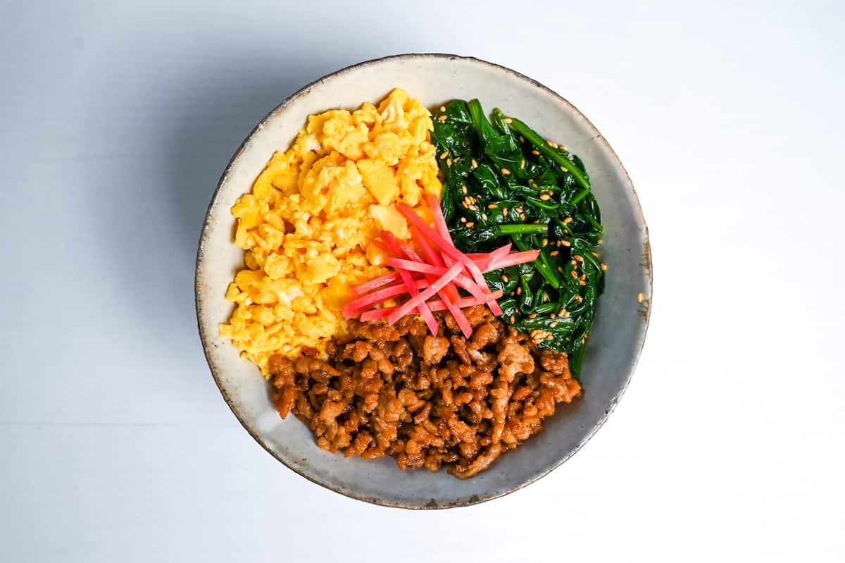 sanshoku don (soboro chicken rice bowl) topped with pink pickled ginger (benishoga)