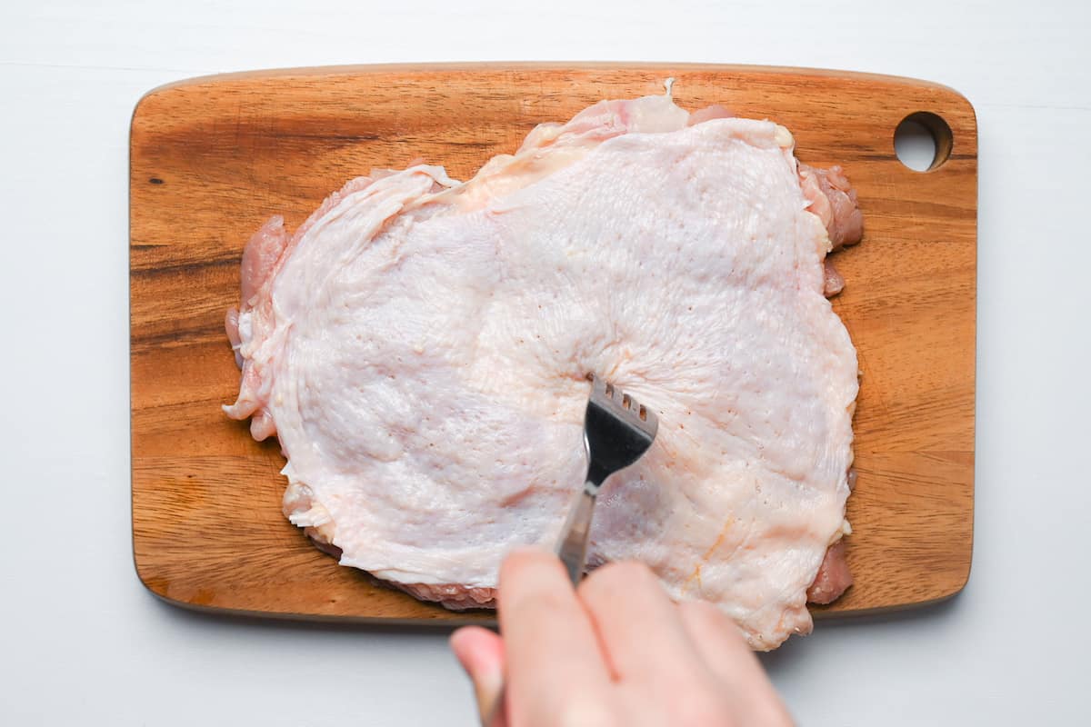 piercing chicken thigh with fork