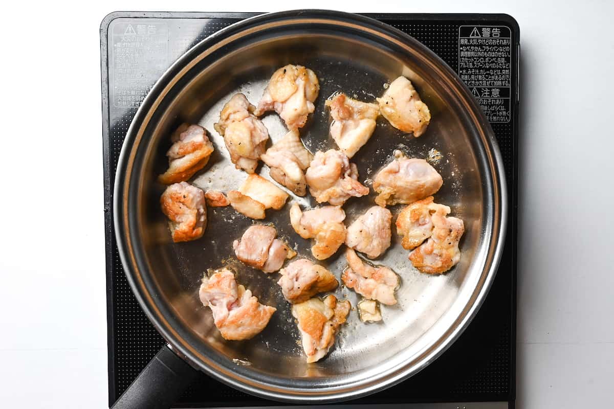 fried chicken thigh pieces cooking in a pan