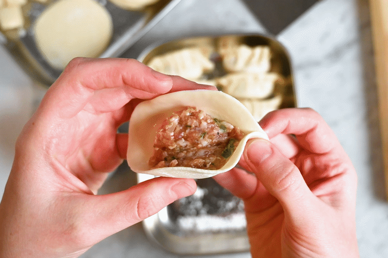 An animated gif showing how to pleat and seal the top of a gyoza wrapper