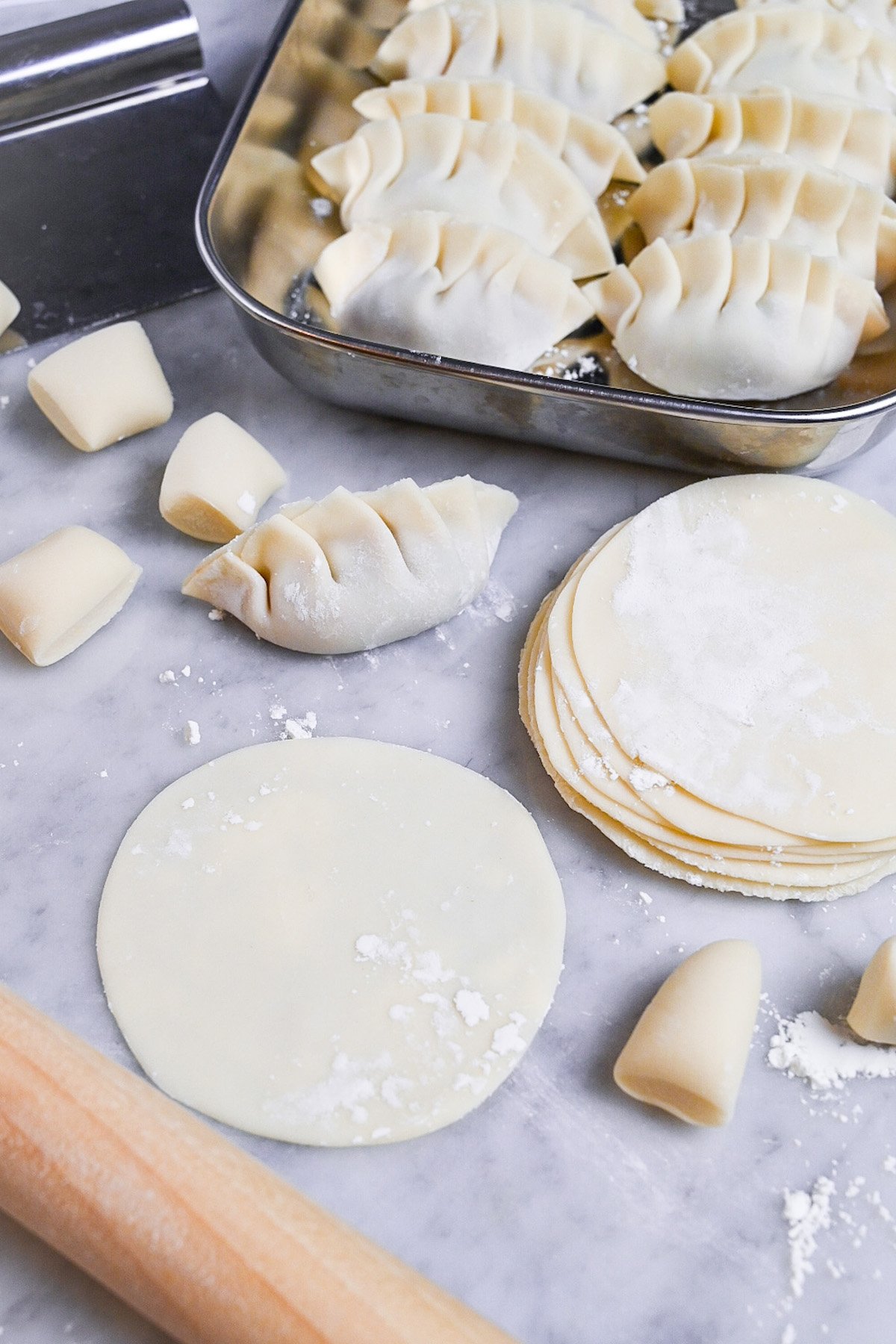 homemade gyoza wrappers in a stack next to a tray of homemade gyoza