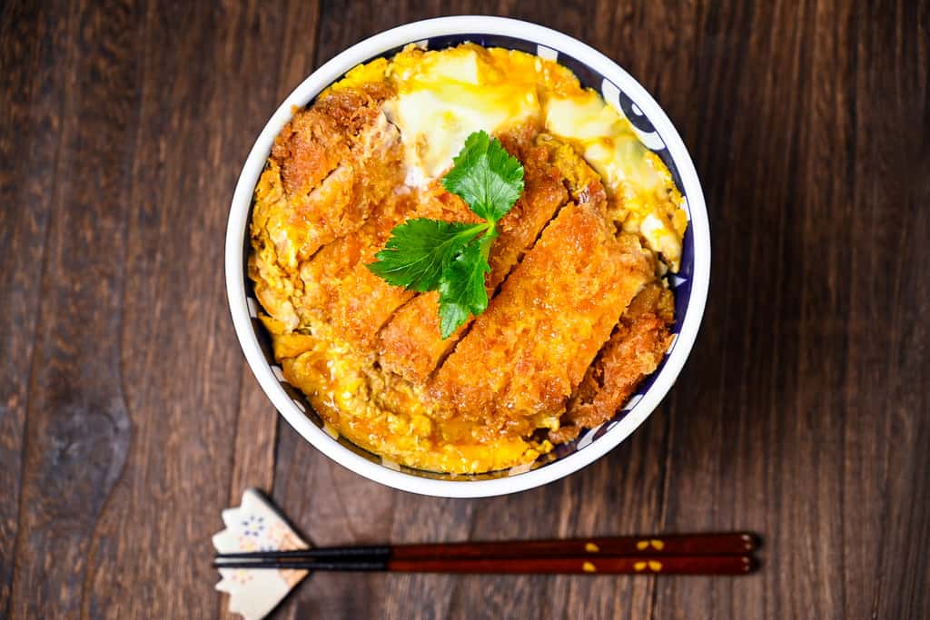 Japanese katsudon served in a blue and white bowl top down view