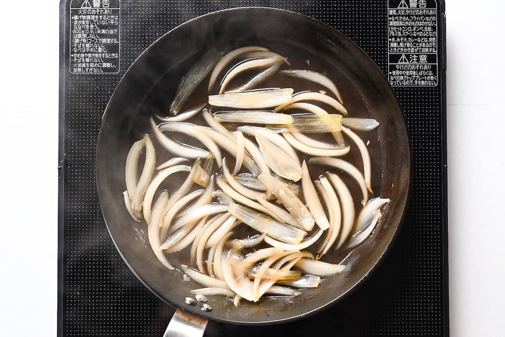 simmering onion in dashi broth for katsudon