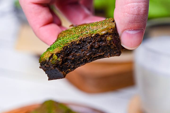 a piece of dark chocolate and matcha brownie with bite