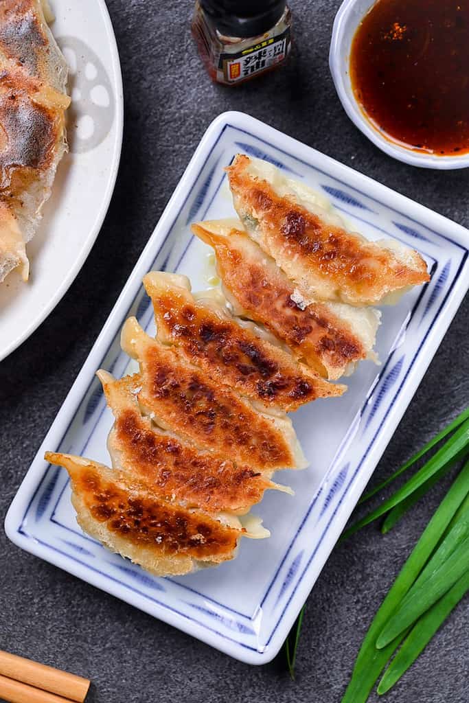Japanese pan fried gyoza dumplings on a white plate with homemade dipping sauce