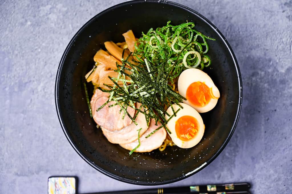 Abura soba topped with chashu, ramen egg, spring onion and menma top down landscape