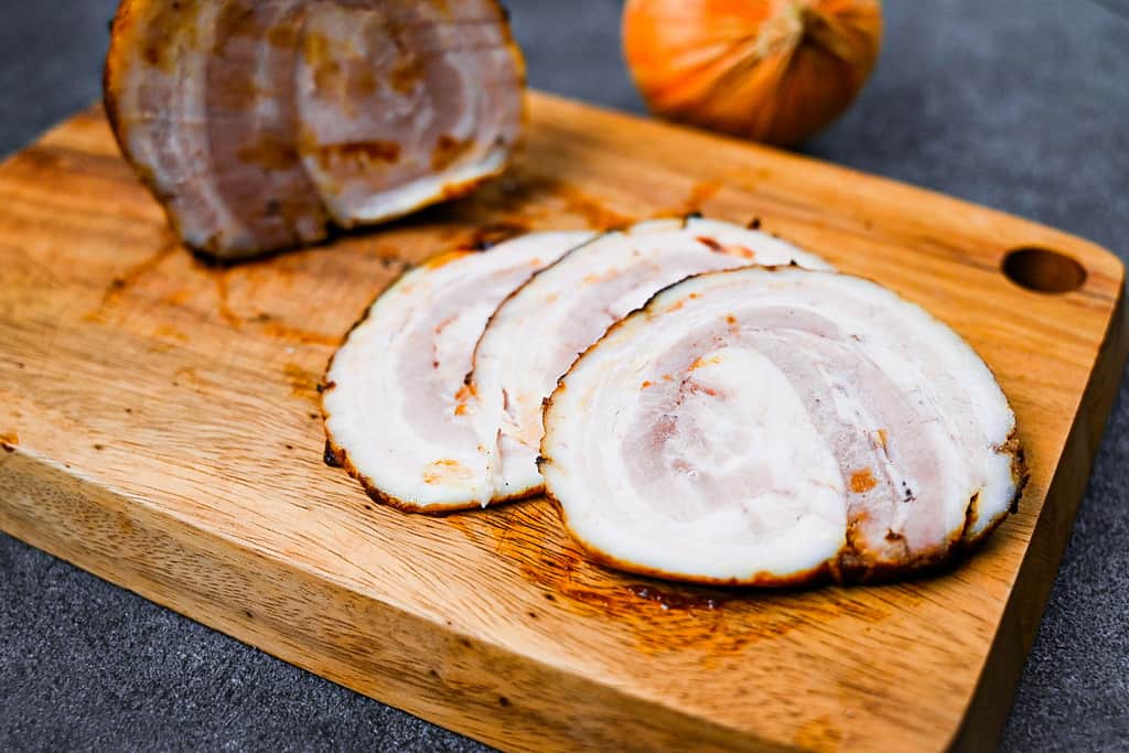 homemade Japanese chashu cut into three slices on a wooden chopping board