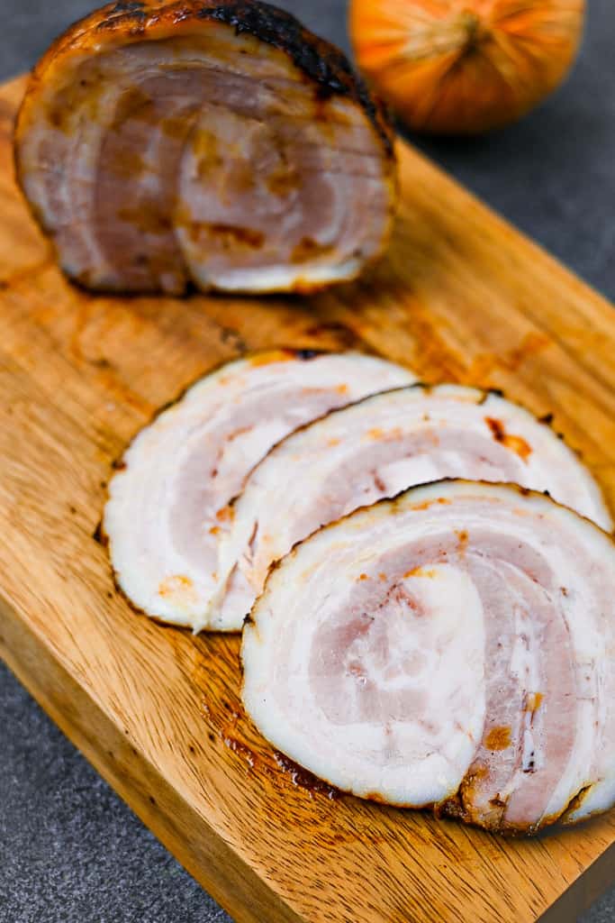 homemade Japanese chashu cut into three slices on a wooden chopping board