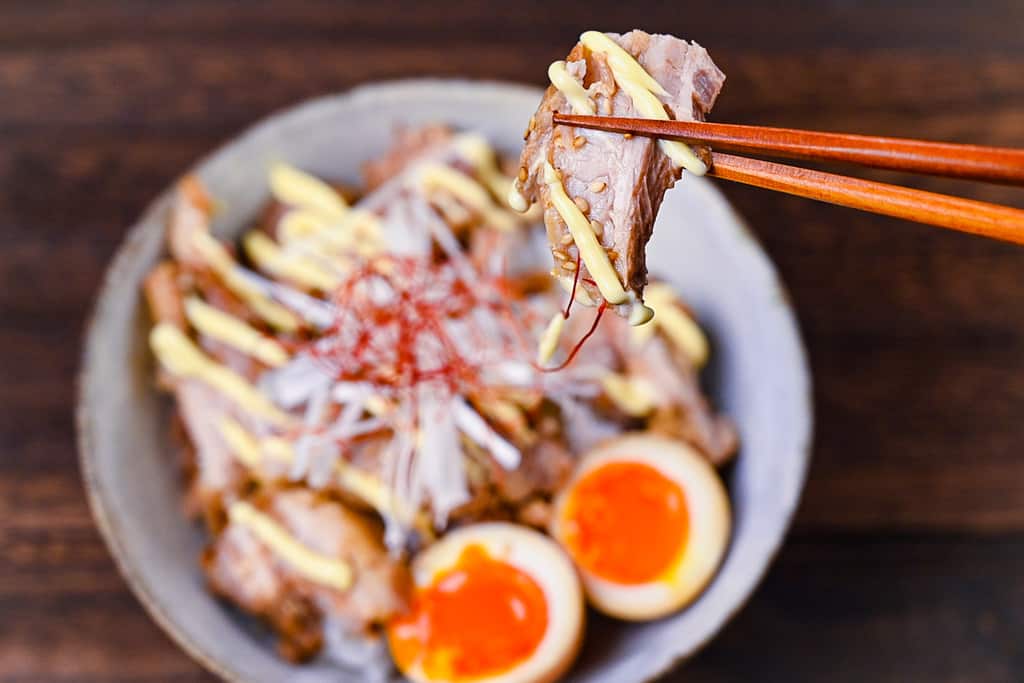 A piece of chashu picked up with chopsticks