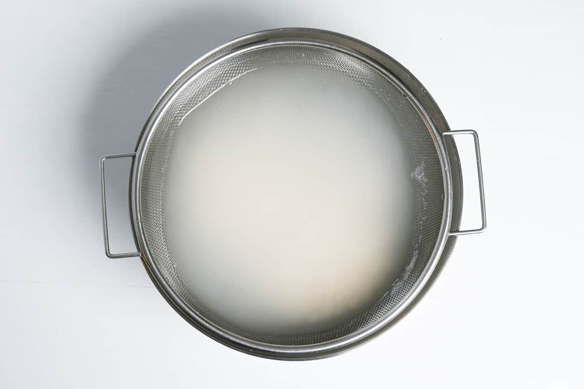 washing rice in a sieve over a mixing bowl