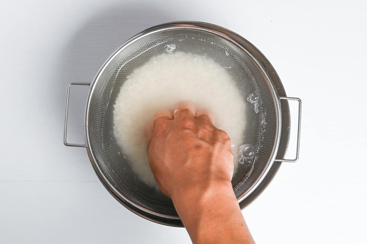 gently washing rice in sieve over bowl of water