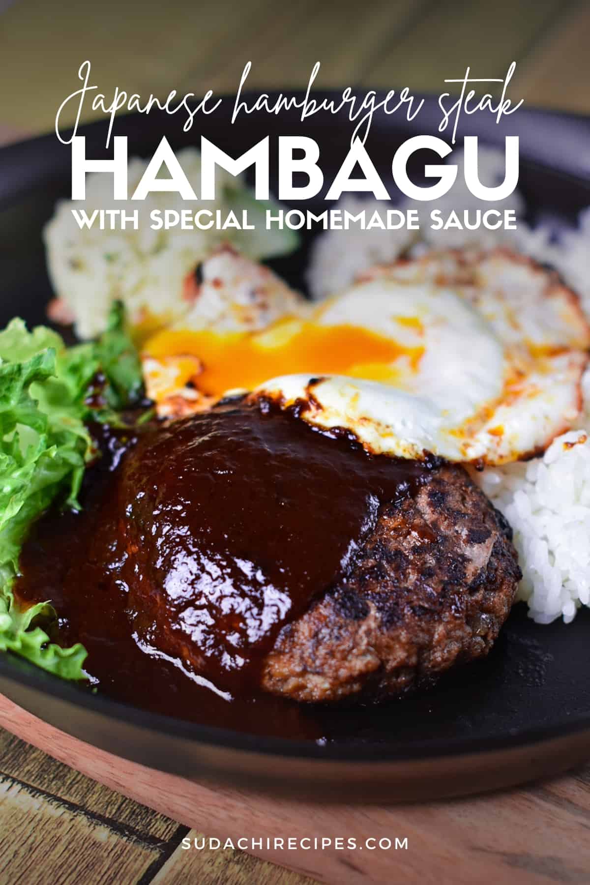 Japanese hambagu steak on a black plate with rice, salad and a fried egg