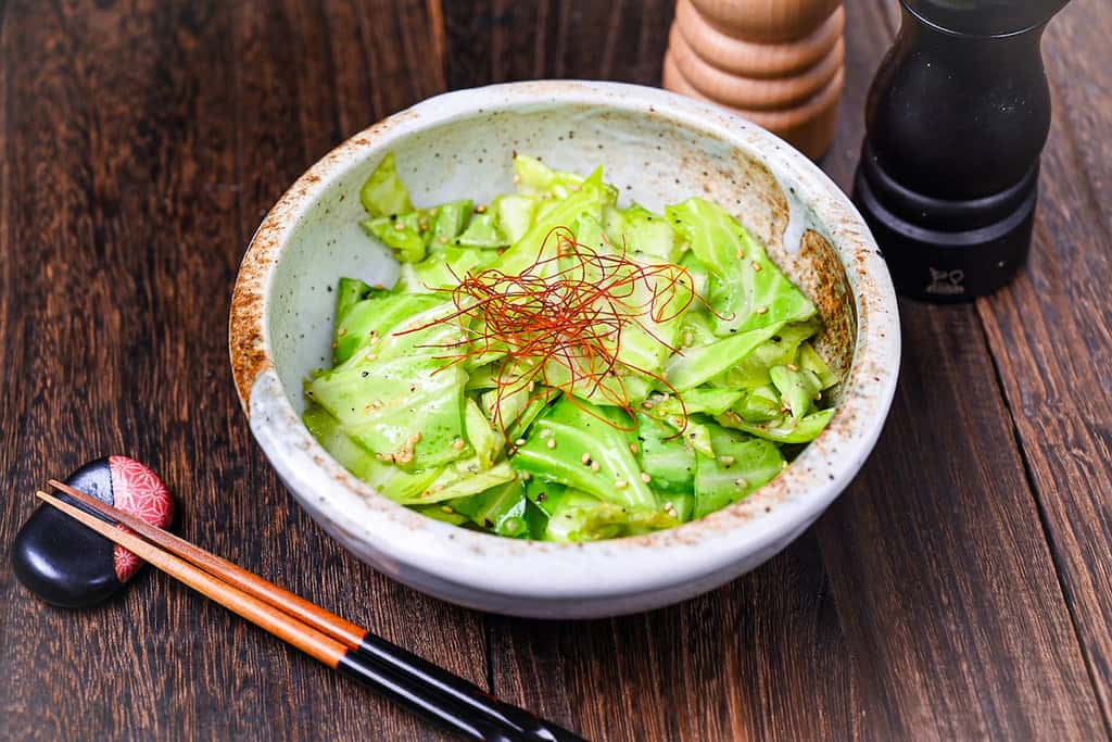 Addictive Japanese Izakaya style salted cabbage in a cream bowl topped with sesame seeds and chili threads