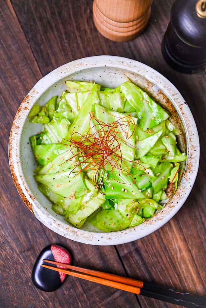 Addictive Japanese Izakaya style salted cabbage in a cream bowl topped with sesame seeds and chili threads
