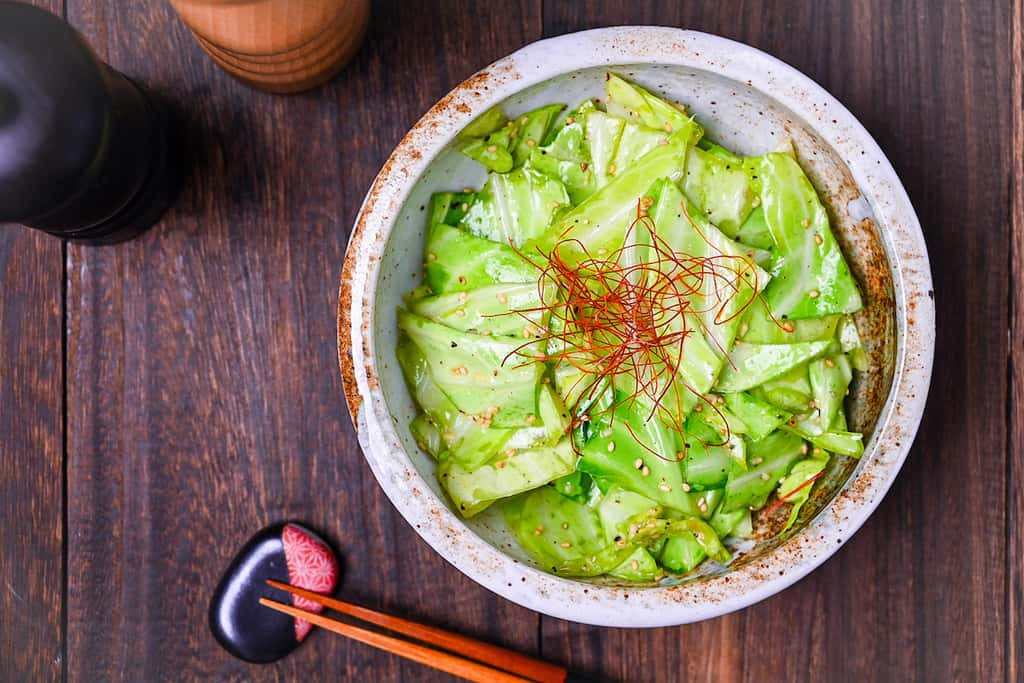 Addictive Japanese Izakaya style salted cabbage in a cream bowl topped with sesame seeds and chili threads