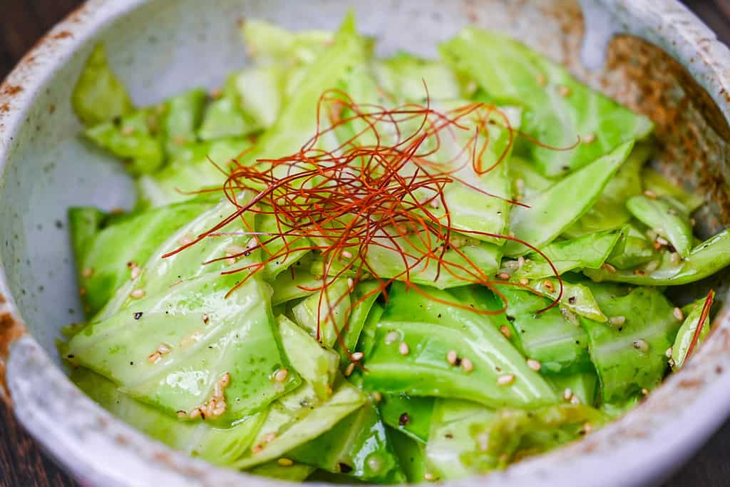 Addictive Japanese Izakaya style salted cabbage in a cream bowl topped with sesame seeds and chili threads