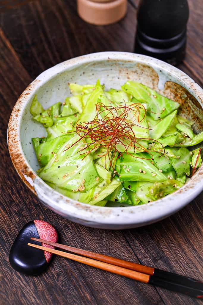 Addictive Japanese Izakaya style salted cabbage in a cream bowl topped with sesame seeds and chili threads