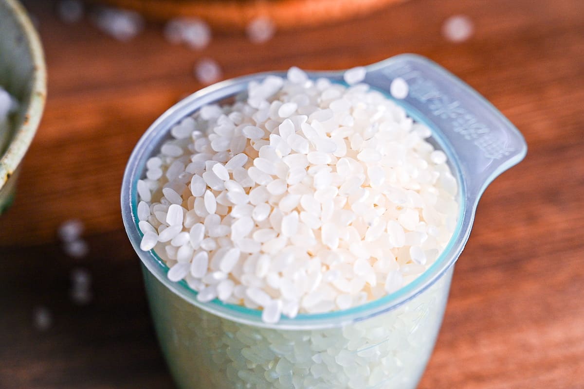 raw Japanese short-grain rice in a green Japanese rice measuring cup