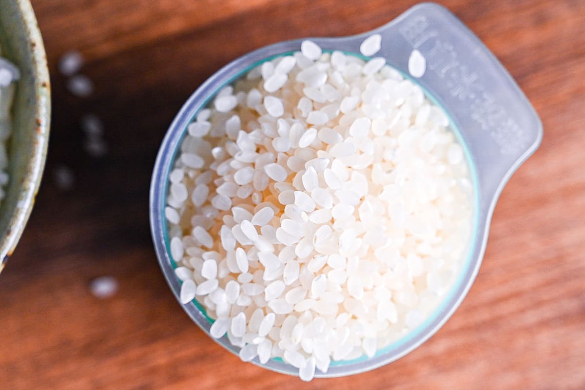 raw Japanese short-grain white rice in a green Japanese rice measuring cup