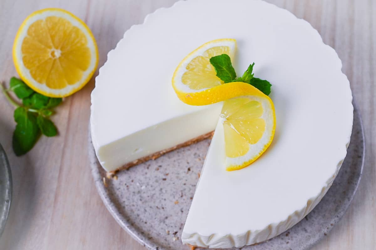no bake lemon rare cheesecake topped with a curled lemon slice and mint leaves