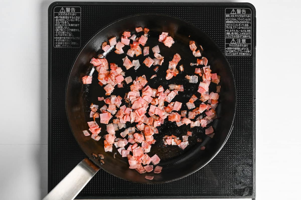 frying bacon (slices cut into squares) in a frying pan