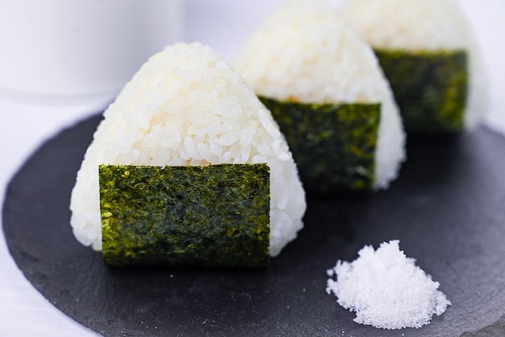 Three salted onigiri rice balls on a round slate plate