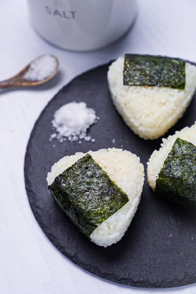 Three salted onigiri rice balls on a round slate plate