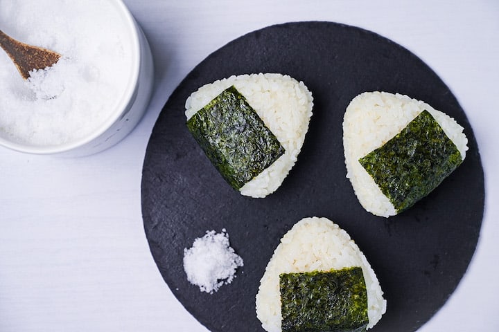 Three salted onigiri rice balls on a round slate plate