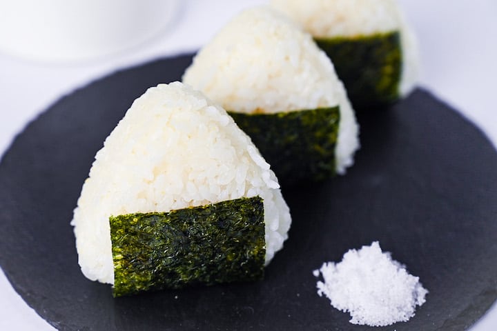 Three salted onigiri rice balls on a round slate plate