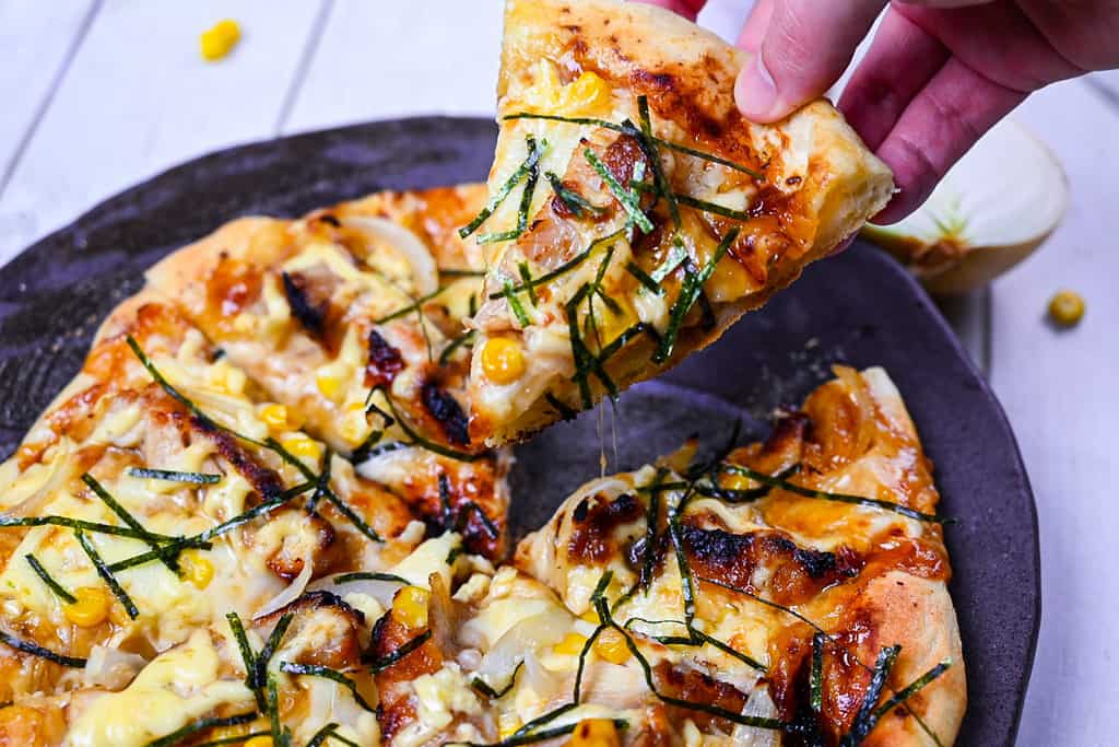 Holding a slice of Japanese Teriyaki Chicken pizza