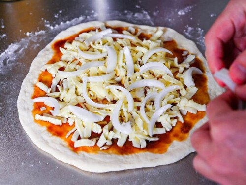 adding sliced onions to teriyaki chicken pizza