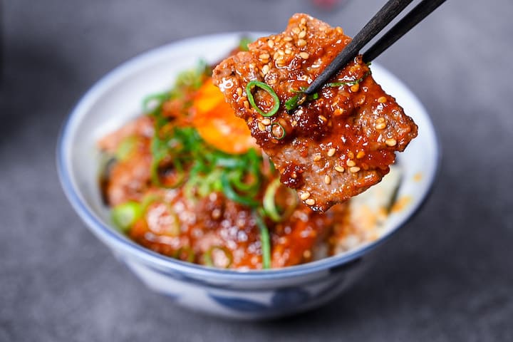 Yakiniku style beef bowl (Yakiniku donburi) topped with spring onion and an egg yolk