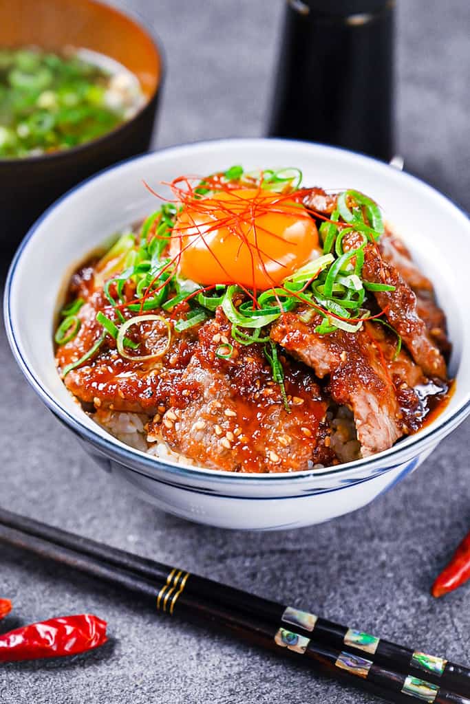 Yakiniku style beef bowl (Yakiniku donburi) topped with spring onion and an egg yolk