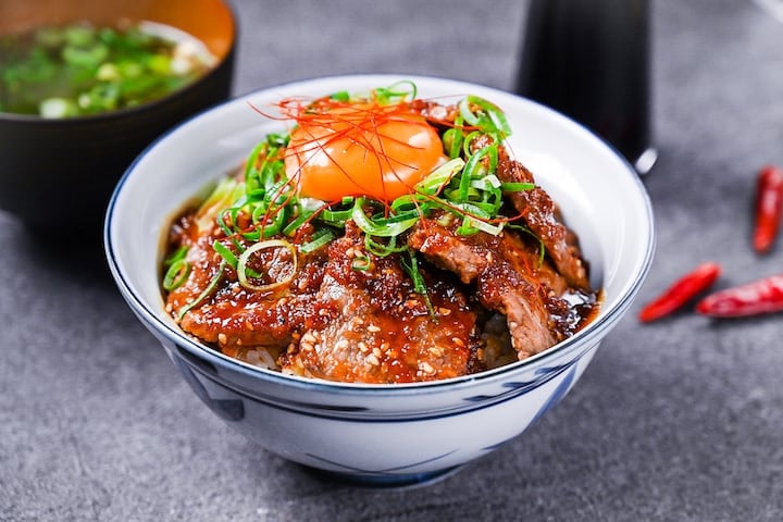 Yakiniku style beef bowl (Yakiniku donburi) topped with spring onion and an egg yolk