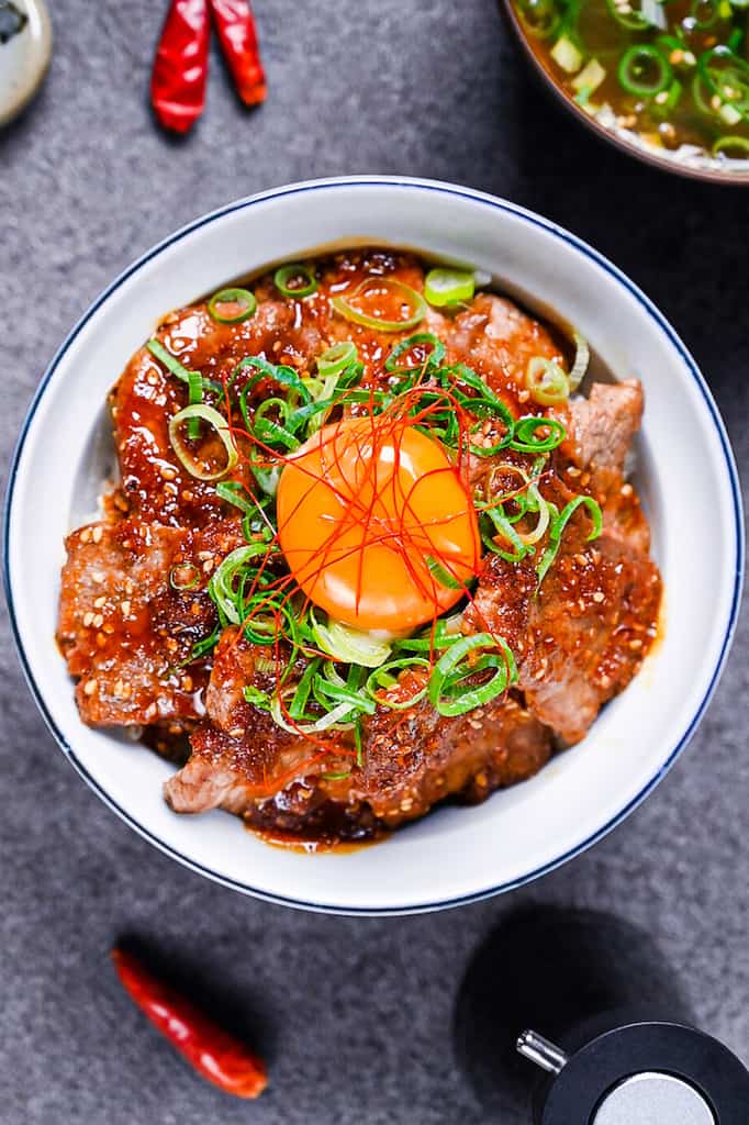 Yakiniku style beef bowl (Yakiniku donburi) topped with spring onion and an egg yolk