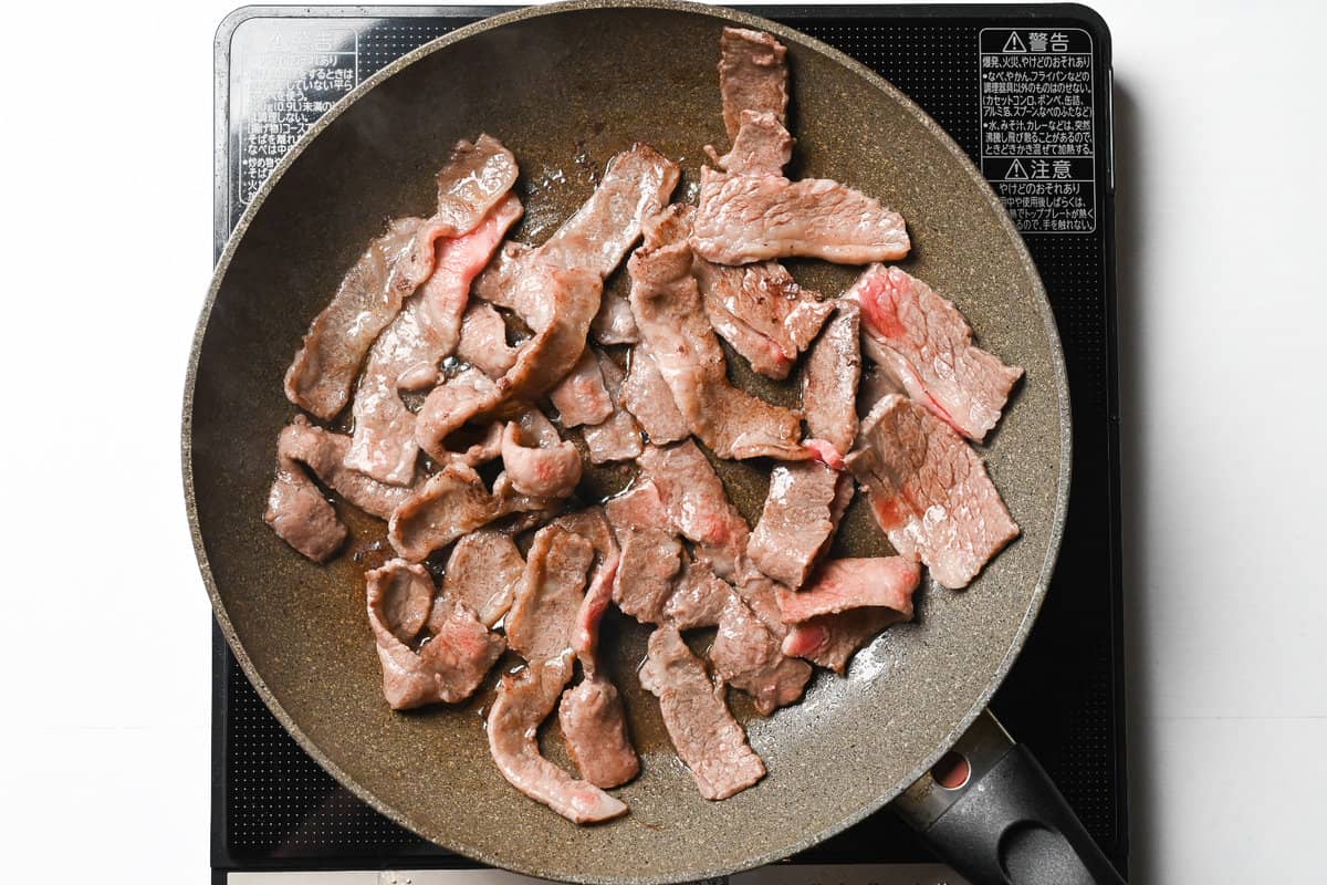 thin slices of yakiniku meat frying in a frying pan
