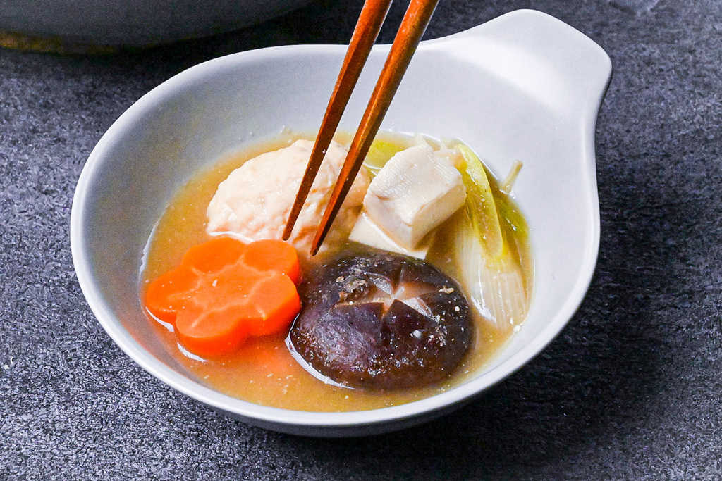 Individual serving of sumo stew with carrot, shiitake tofu and spring onion