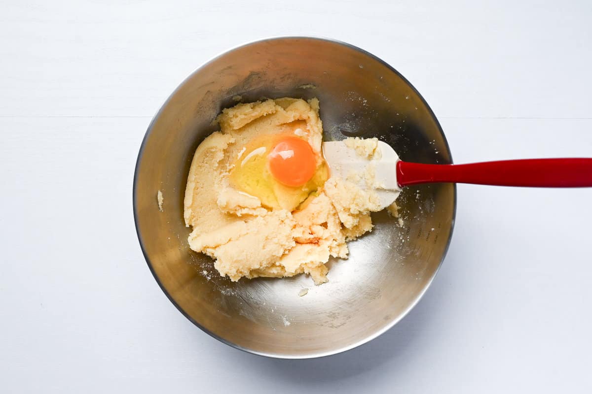 Adding egg and vanilla to cookie dough mixture in a mixing bowl