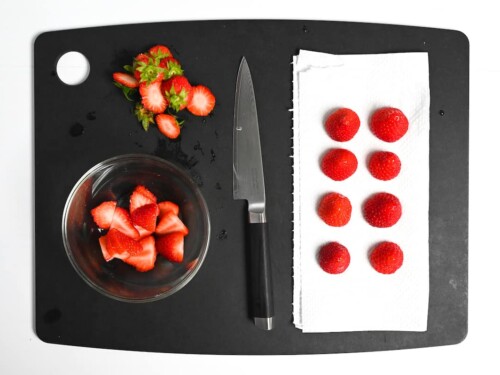 Cut strawberries on a black chopping board