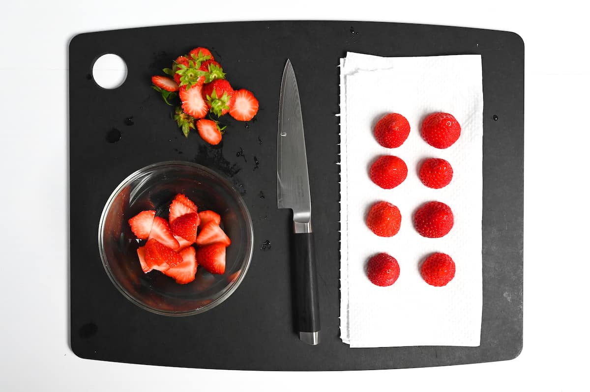 Cut strawberries on a black chopping board