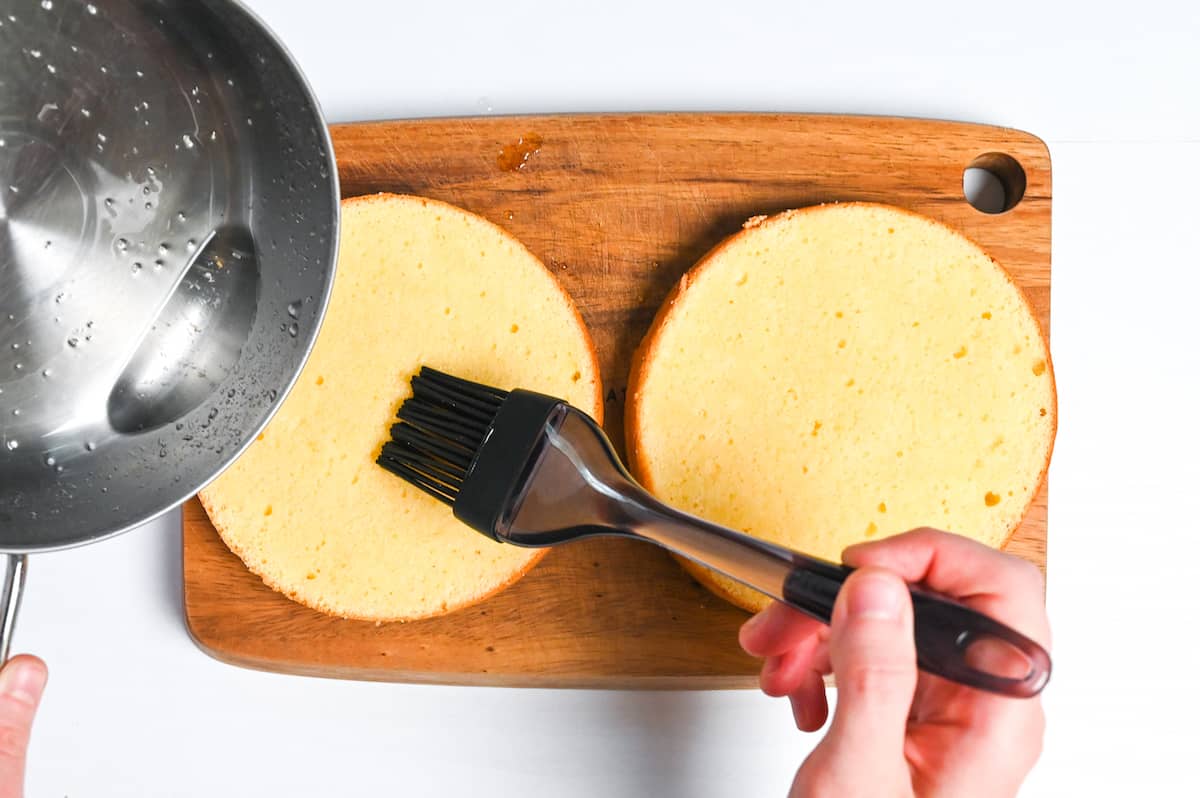 Brushing syrup over surface of genoise sponge