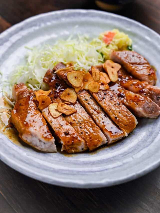 Tonteki Japanese pork steak served with fried garlic chips, shredded cabbage and potato salad